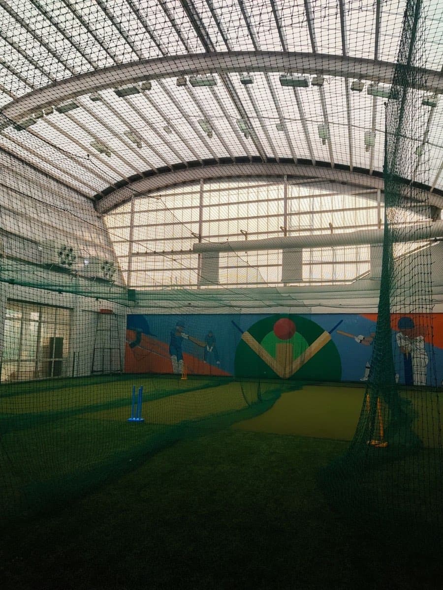 Indoor cricket hall with netted lanes and stumps