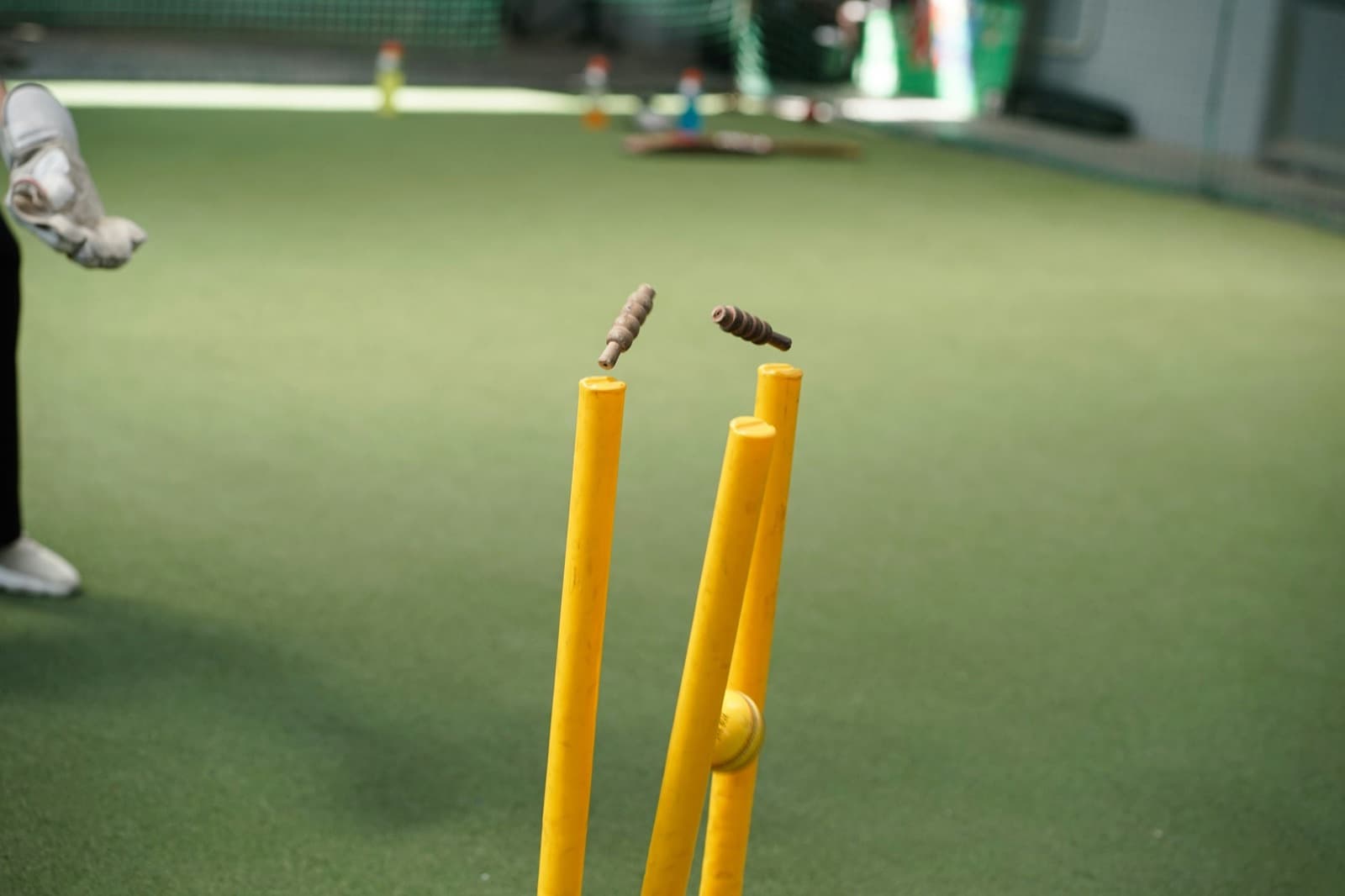 Bails flying as a ball hits the stumps on indoor turf